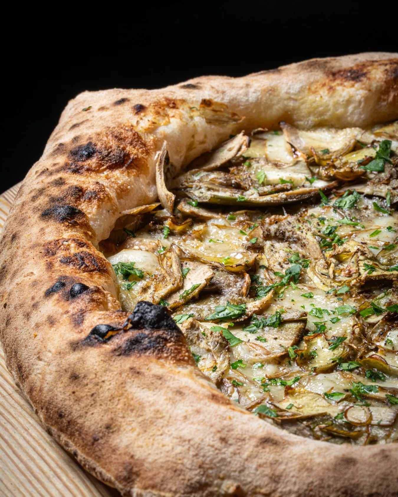 Artichoke and herb pizza on a wooden peel, fresh from the wood-fired oven