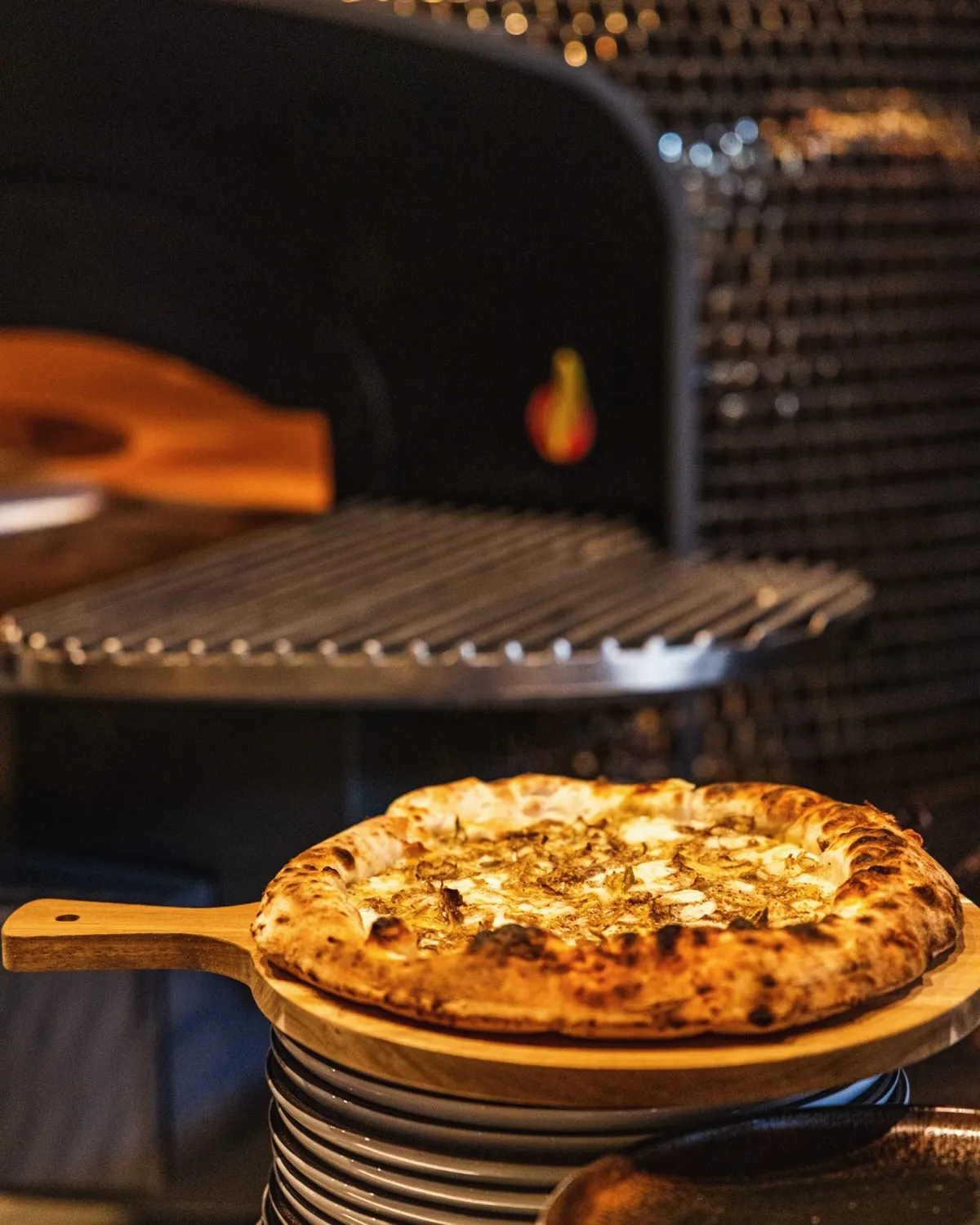 Wood-fired pizza on a peel beside the glowing hearth at Francesco Martucci Wynwood